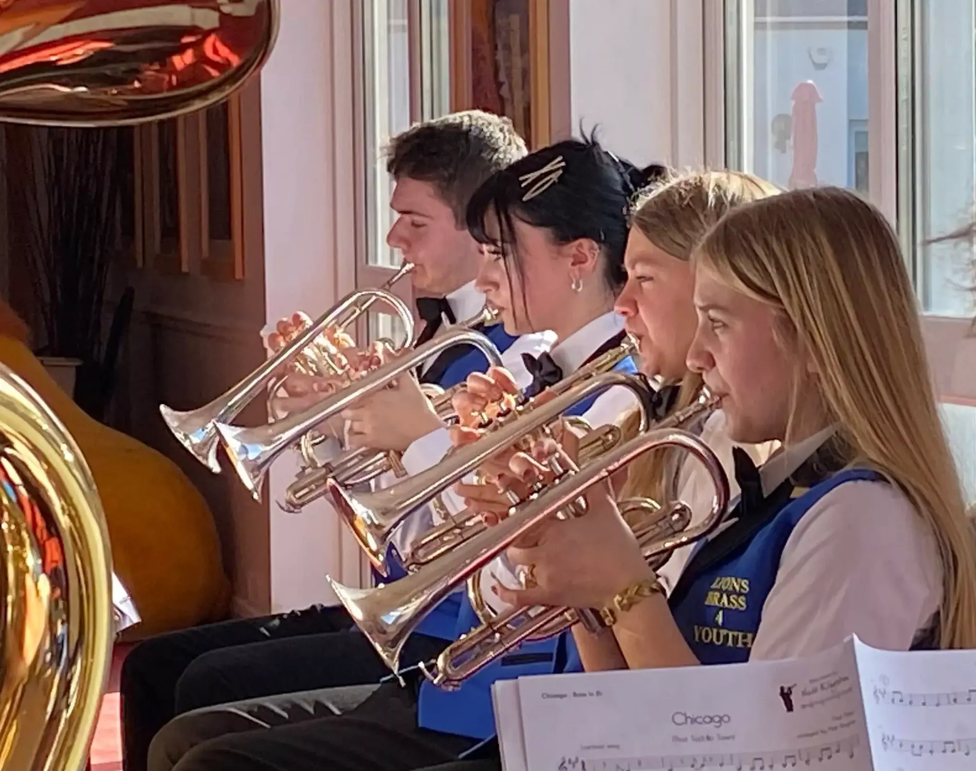 Lions Brass 4 Youth band members standing on a wooden bridge over a pond